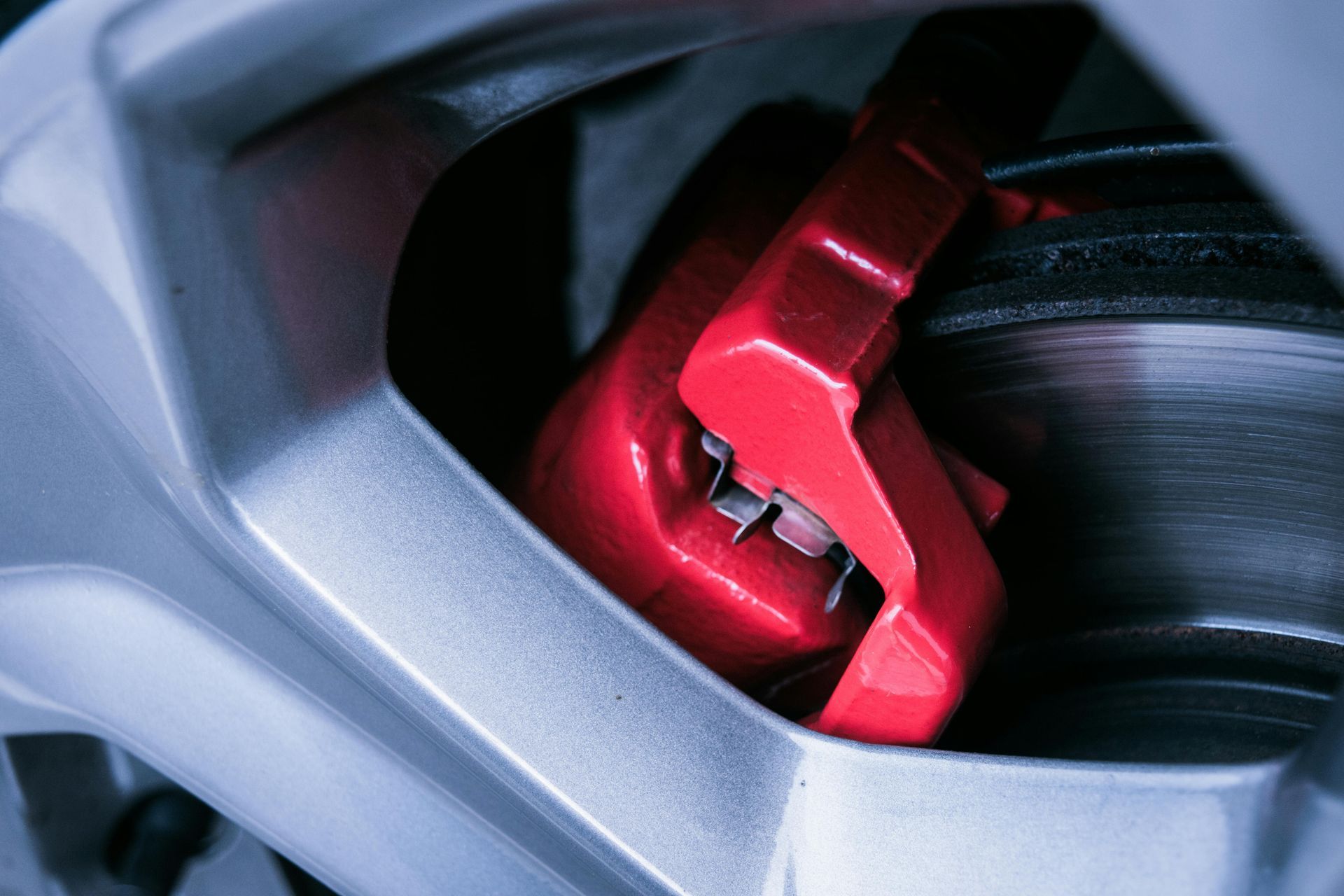 Red brake caliper on a silver car wheel.