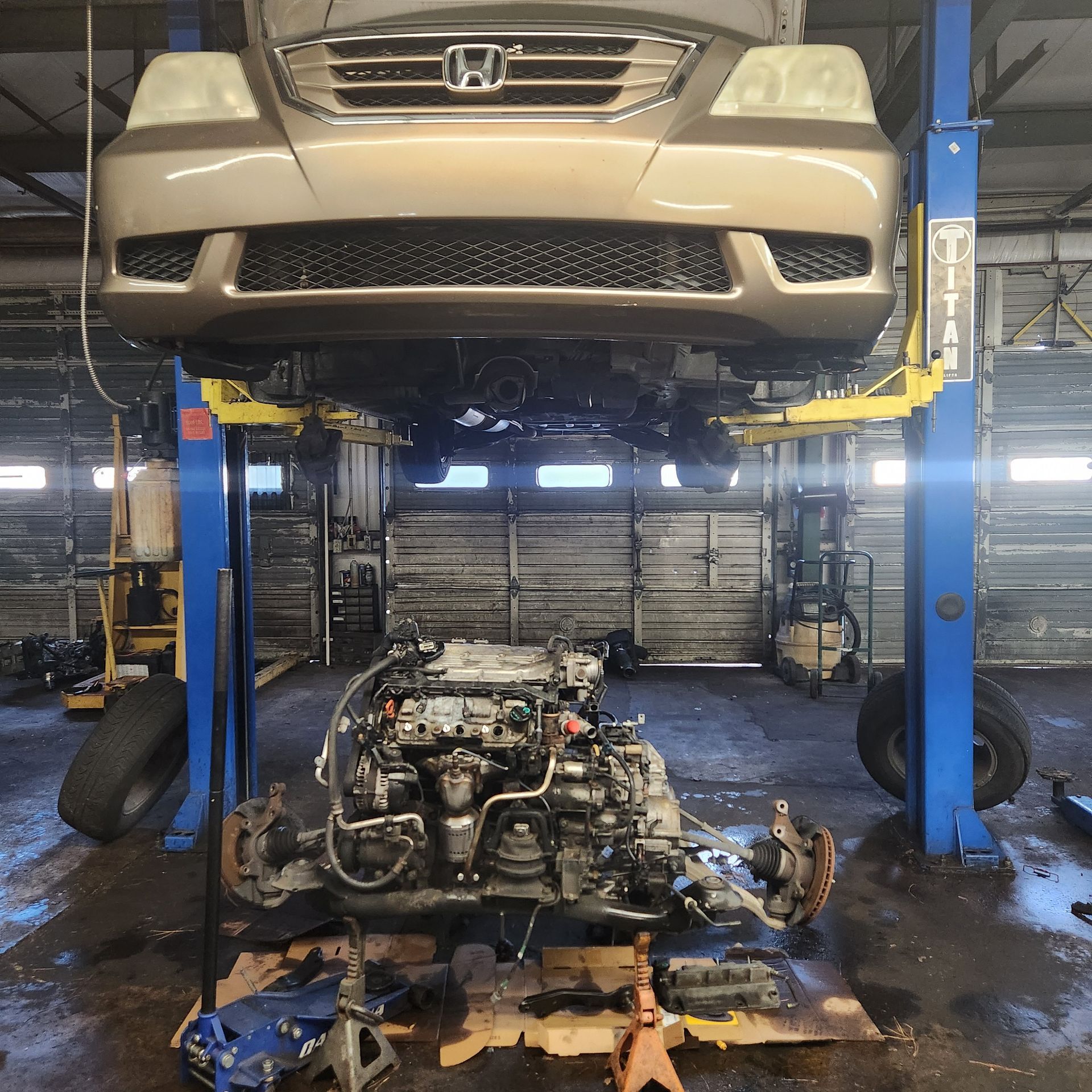 Honda SUV on a lift with its engine removed, in a repair shop.